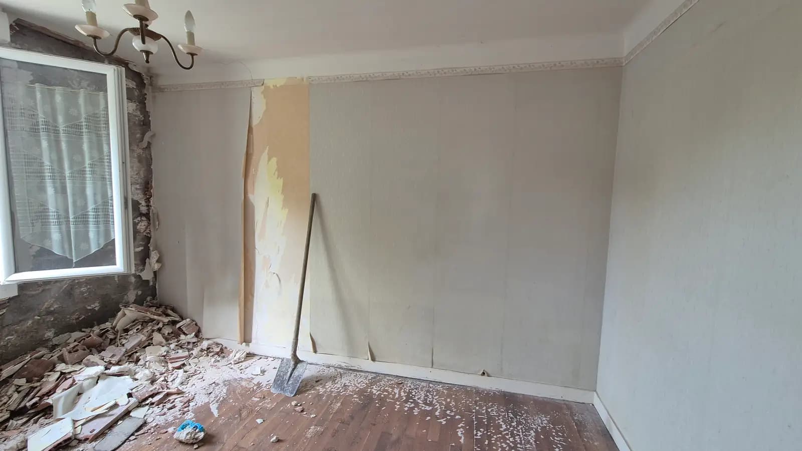 Une cloison déposée en cours de chantier, gravats au sol et reprise à faire
